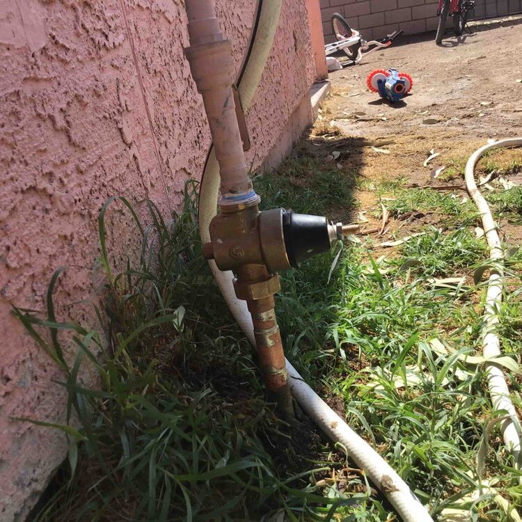 Plumber in Red Rock, AZ installing residential pressure regulator valve on exterior water line